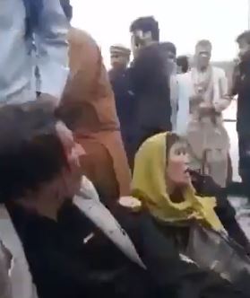 Injured people sit among the crowds outside the airport