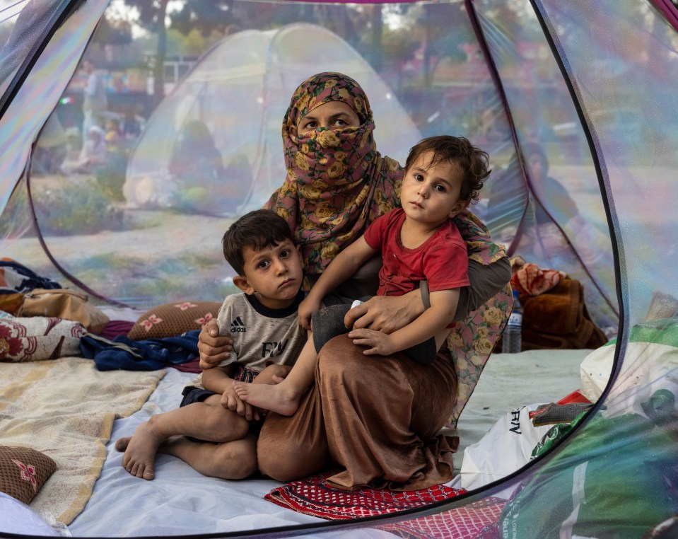 A woman cowers with her children as they flee the Taliban