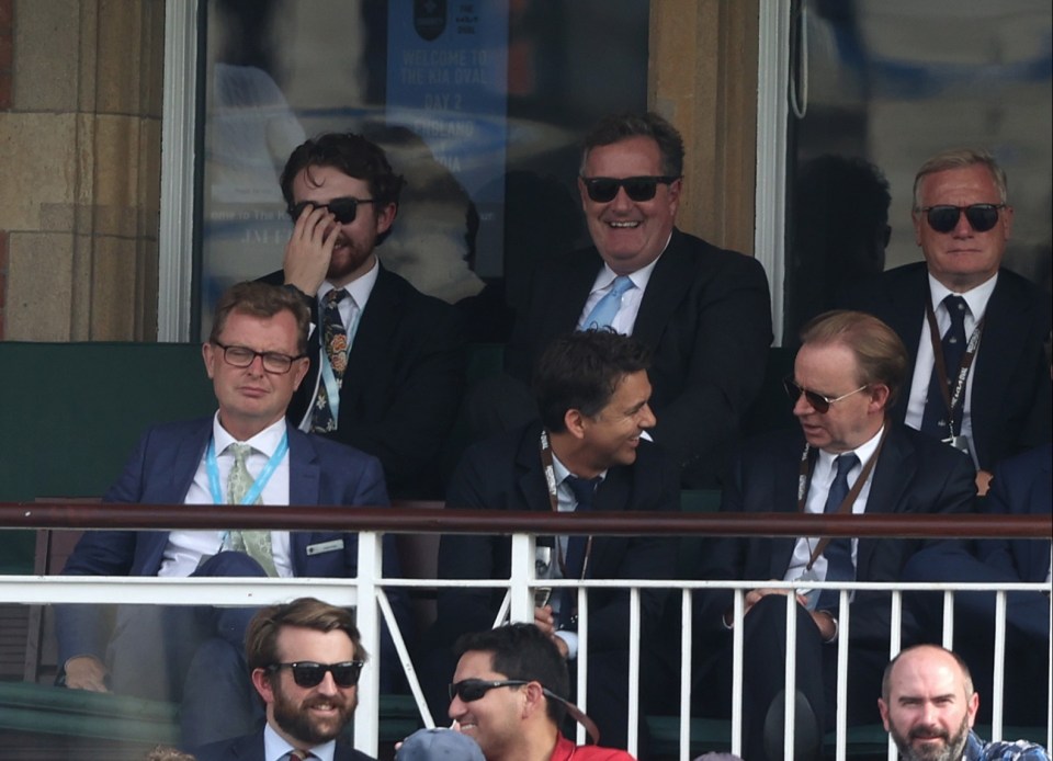 Piers was snapped grinning and checking his phone during the match