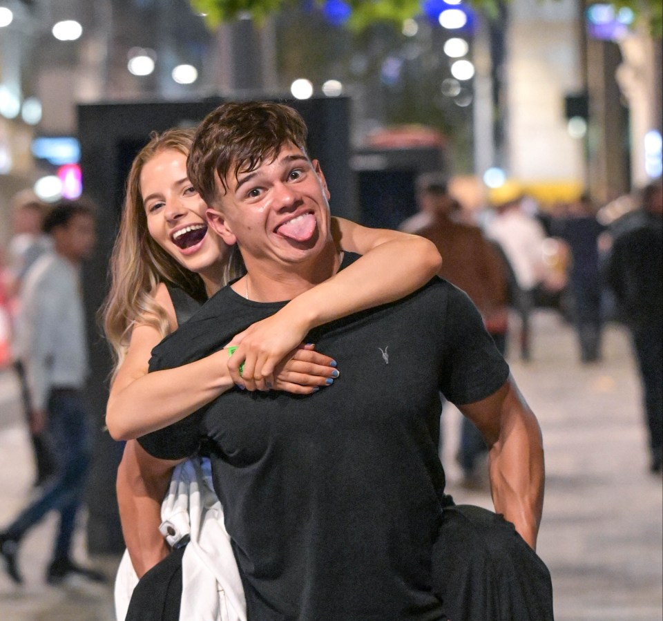 A lad gives his female friend a joyful piggyback on Broad Street in Birmingham