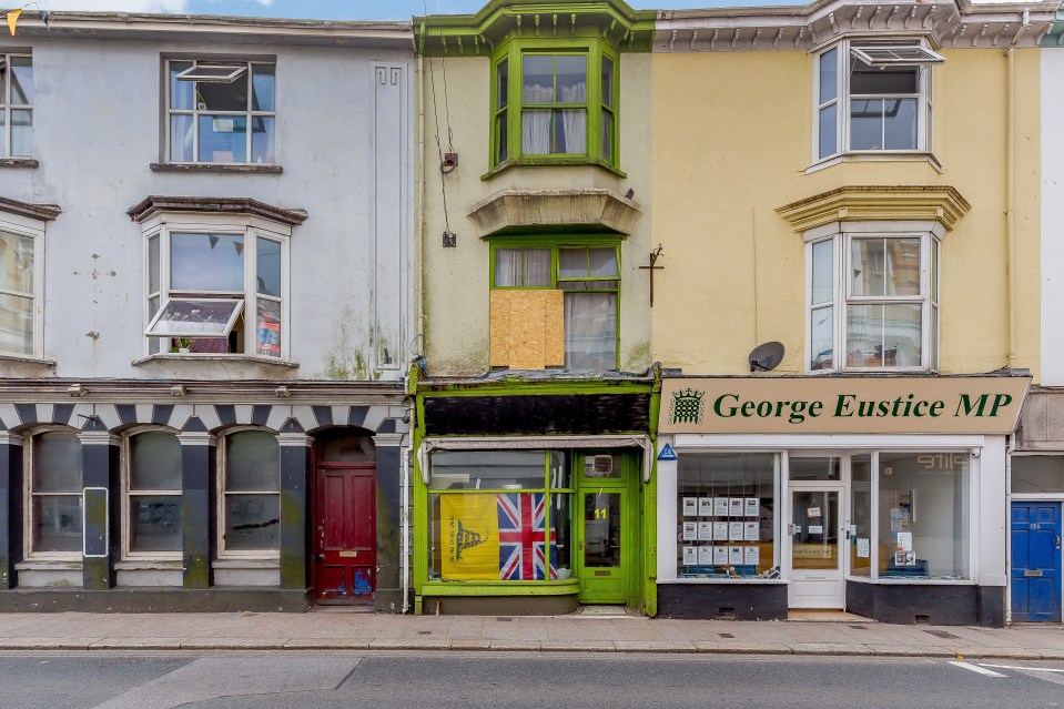 The house has a boarded-up window and a lime-green exterior