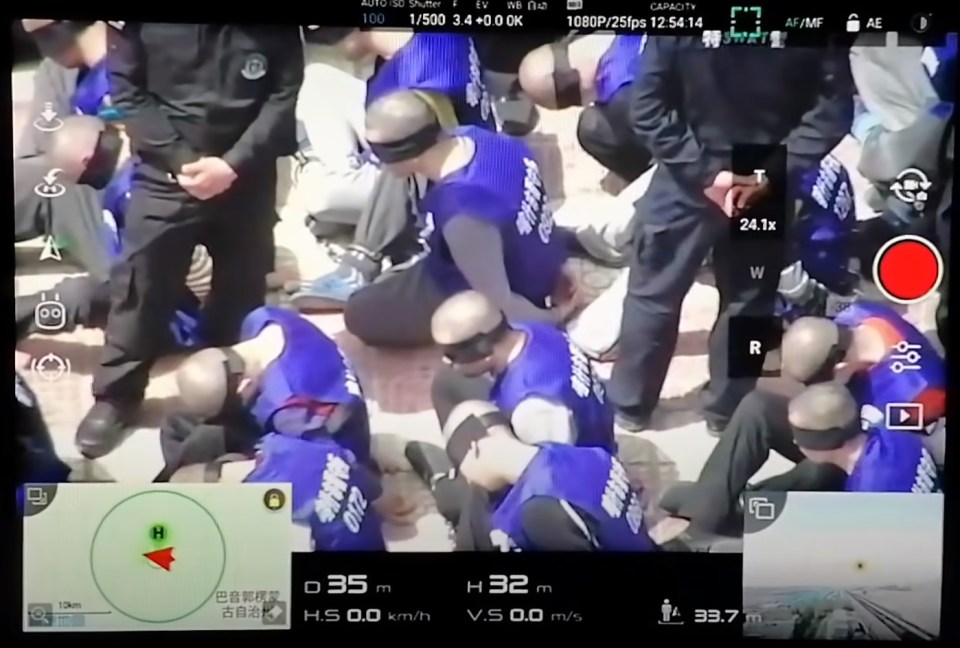 Drone footage has captured the moment hundreds of blindfolded and shackled prisoners are taken away to re-education camps