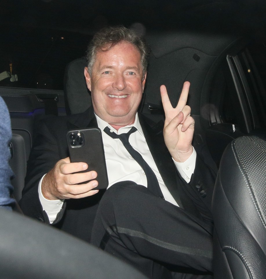 A smiling Piers Morgan waits in a cab after his Ofcom win earlier on Wednesday