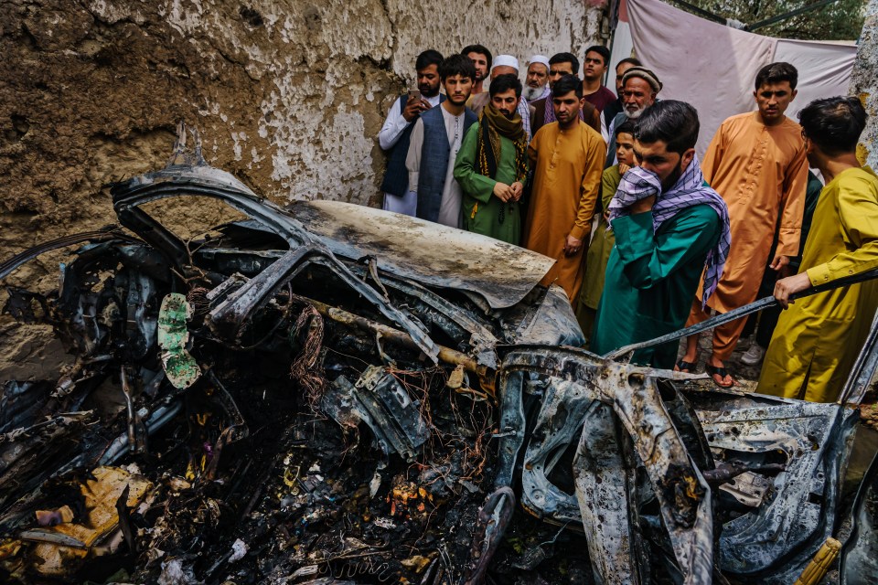 Relatives and neighbors of the Ahmadi family gathered around the incinerated husk of a vehicle targeted and hit by a US drone strike that was supposed to target ISIS-K suicide bombers