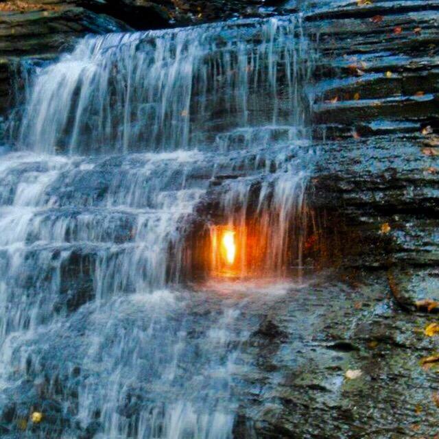 A flame burns behind a waterfall in New York all year round