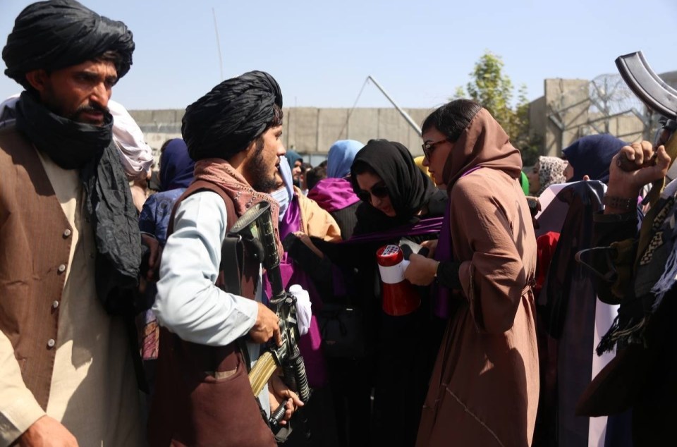 Taliban fighters confront the women marching in the protest