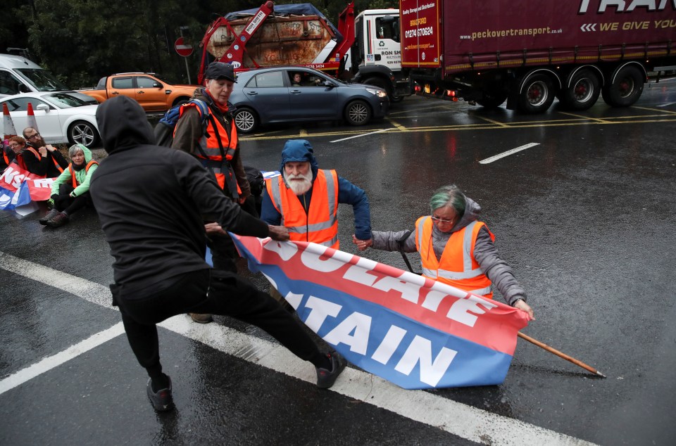 An angry driver rips a banner away from the protesters