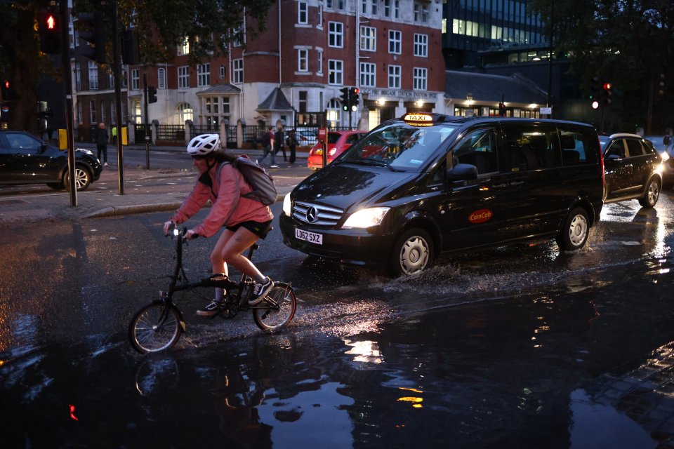 A cyclist rides through surface water in Euston, London