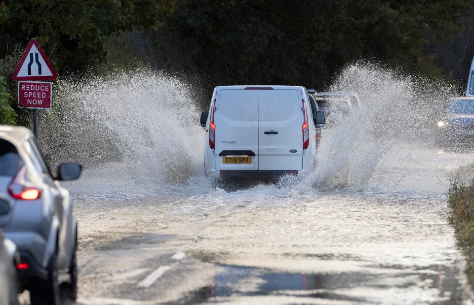 A van splashes through flood water near Lingfield in Surrey