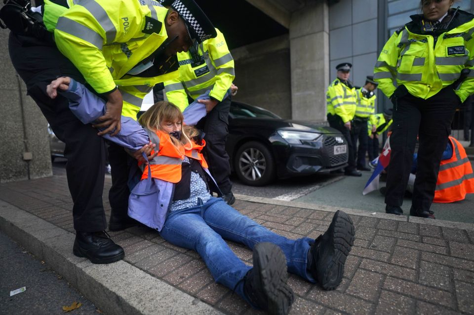 A woman is dragged away from the road after demonstrators blocked traffic