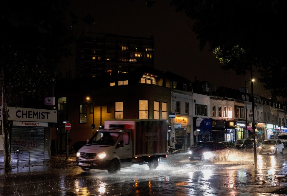 Vehicles are seen passing through flooded road in South East London