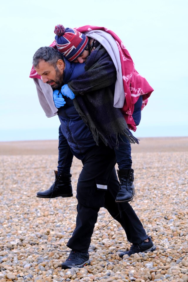 An exhausted woman is carried to shore after crossing the Channel