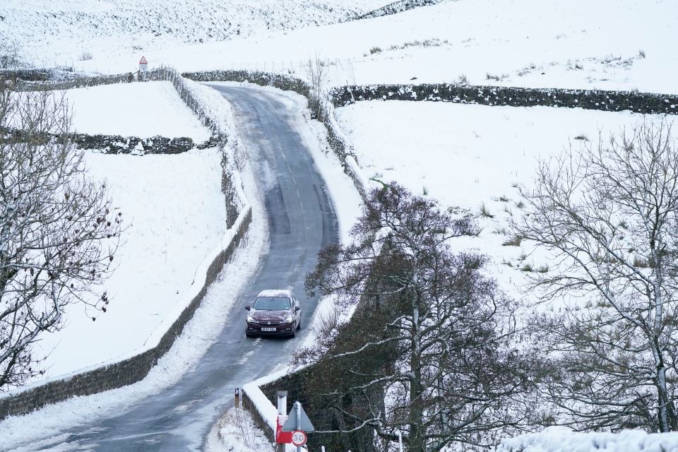 A car drives along an icy road through High Green in the Yorkshire Dales