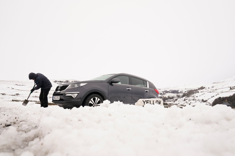 A man digs out a car from snow in High Green in the Yorkshire Dales