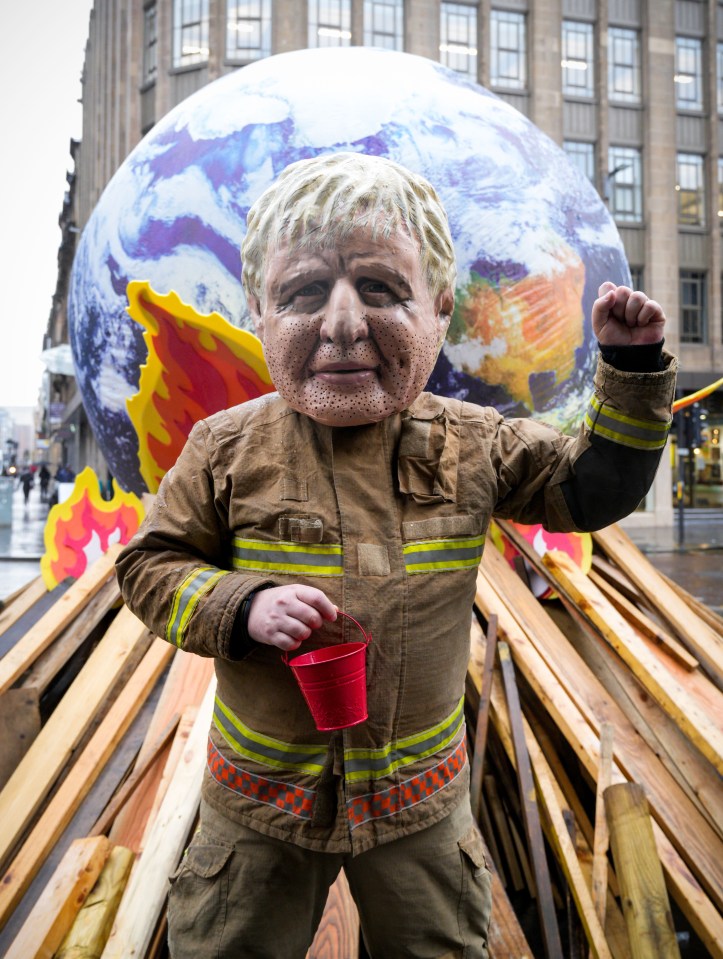 An Oxfam protester dresses as a firefighter Boris Johnson amid claims COP26 was heading towards failure