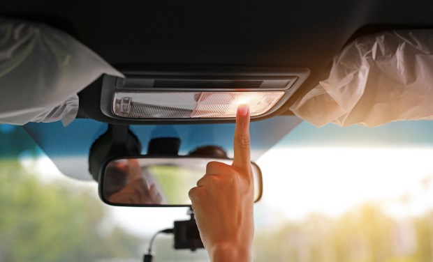 a person is pressing a button on the ceiling light of a car