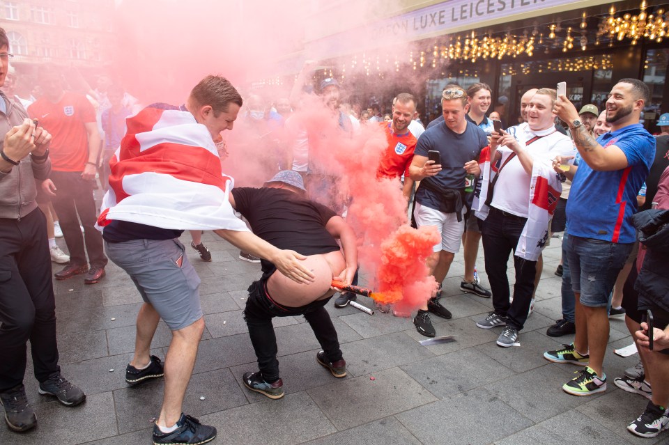 A drunk fan was pictured with a flare in his bottom before the game