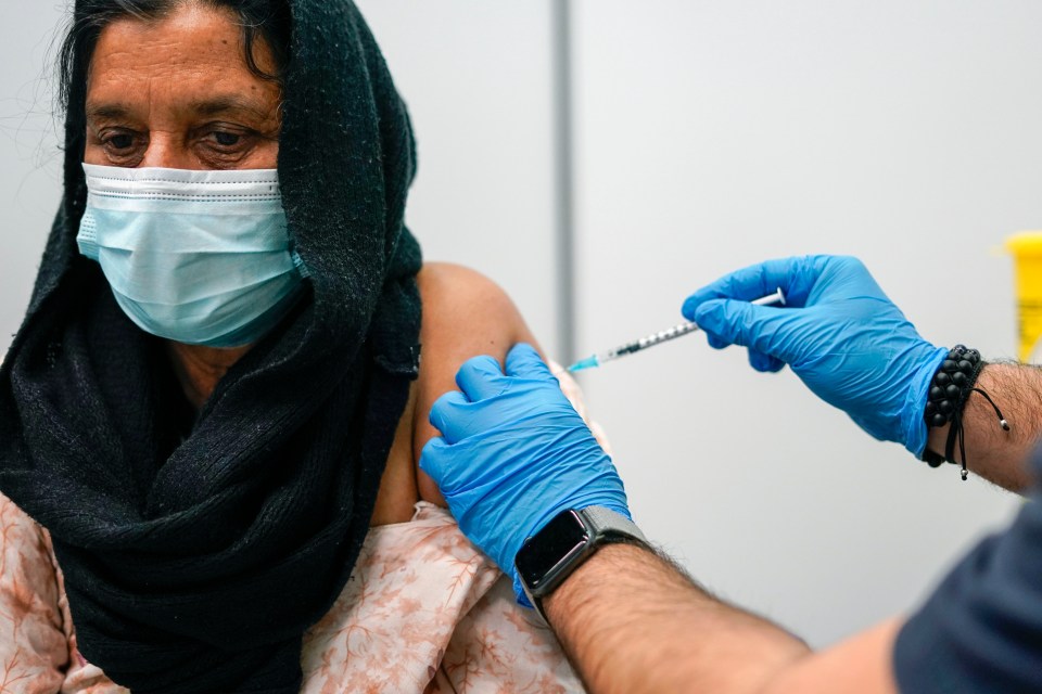 A patient receives a dose of the Pfizer COVID-19 vaccine at Swaminarayan School vaccination centre, in London