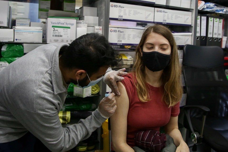 An NHS vaccinator administers the Moderna Covid-19 booster jab at a centre in north London