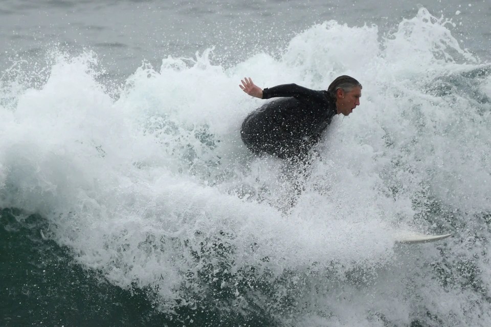 A surfer catching a wave Manhattan Beach, California, despite warnings to stay away from the coast