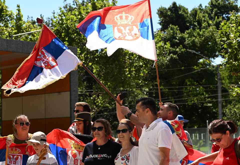 Supporters of Novak Djokovic hold national flags as they gather in front of Federal Court