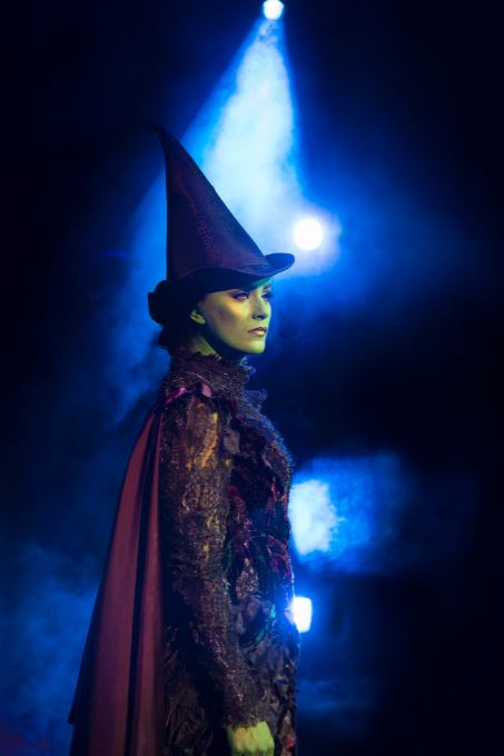 a woman in a witch costume is standing in front of a blue light