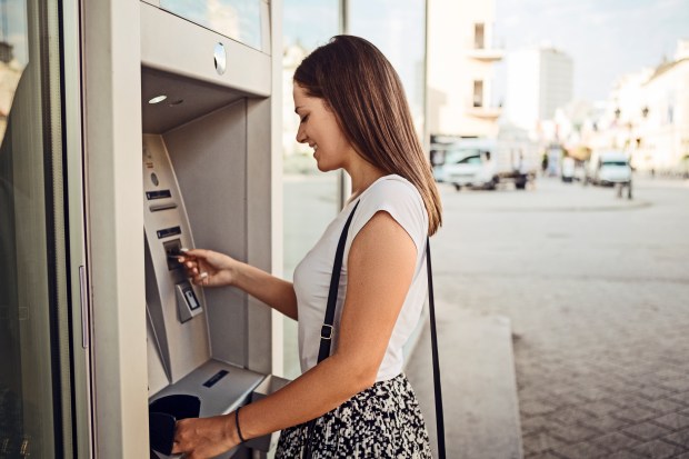 a woman inserts a credit card into an atm machine