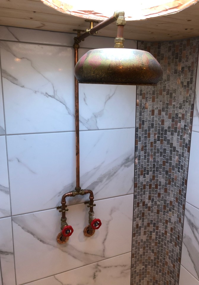 The bathroom has a modern finish with copper taps and shower head