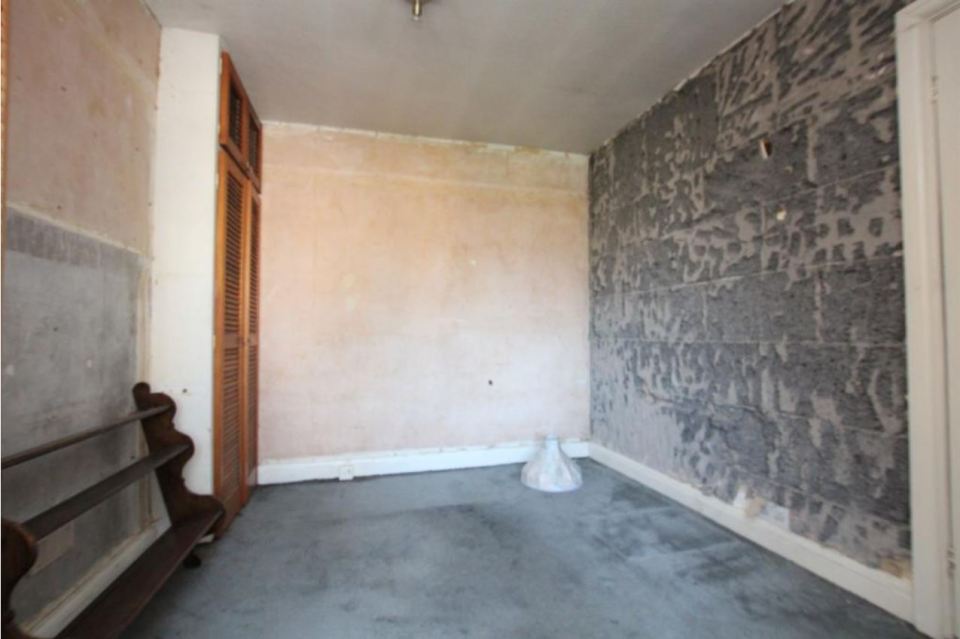 A small rooms still has some of its old rotting wallpaper and carpets