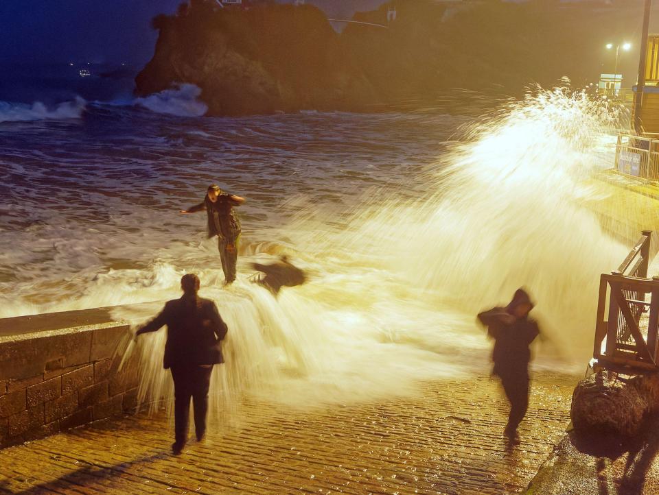 This is the moment a young woman was swept into the sea in as she watched the waves