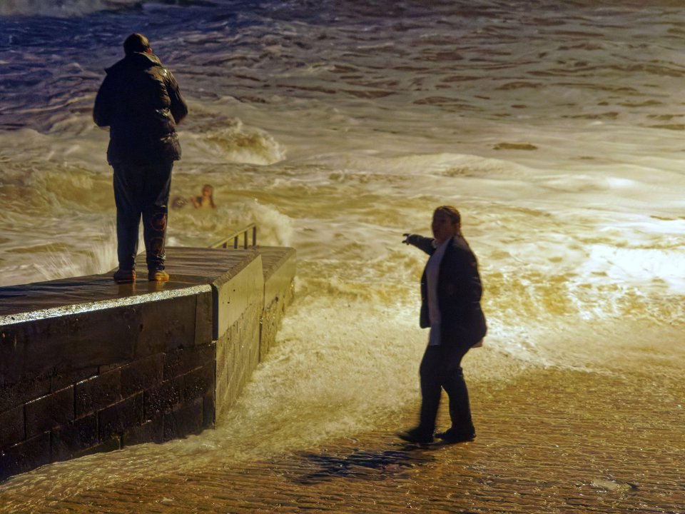 The group gesture at the girl as she's pulled out by the waves