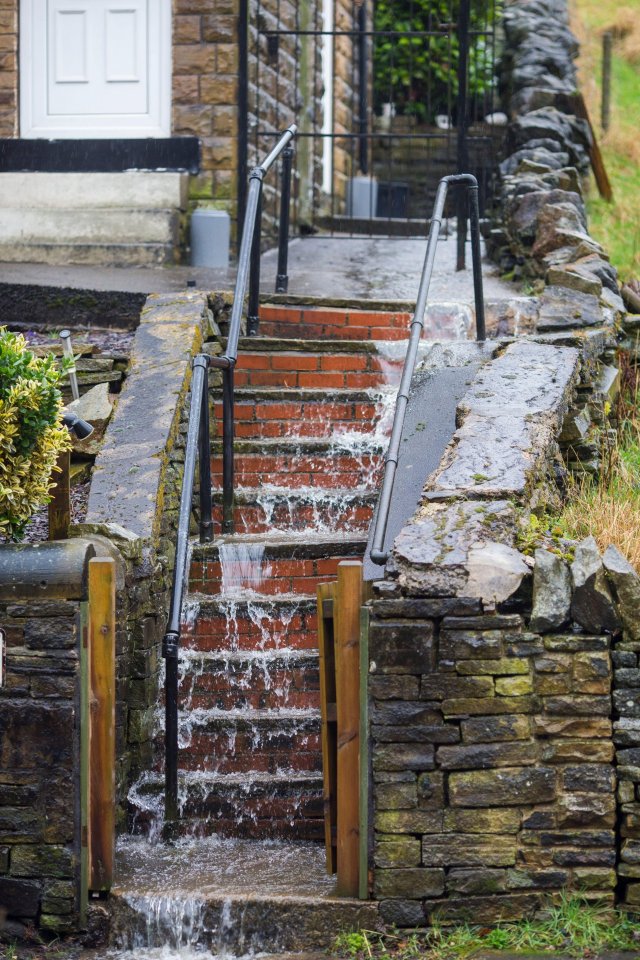 Flood water runs down the steps of a house in Halifax, West Yorkshire,