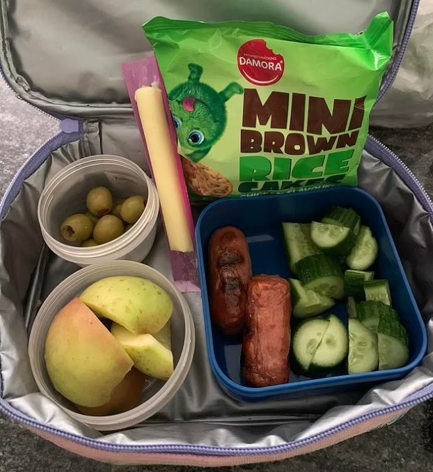 The mum shared the lunchbox and its contents; a sliced apple, olives, cucumber, sausages, rice cakes and a cheese stick