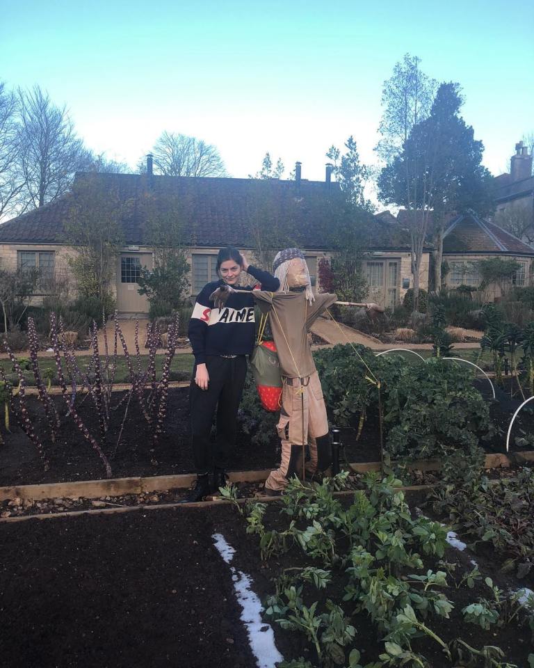 She proudly poses by a scarecrow in her allotment