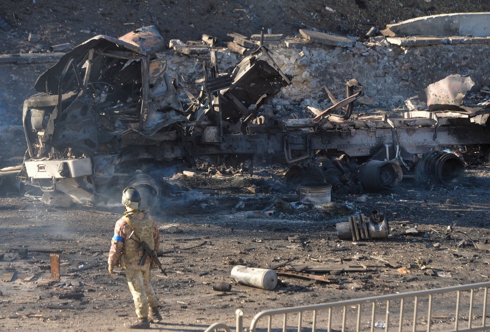 A Ukrainian soldier stands in the charred remains of a battlefield