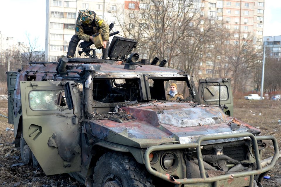 Ukrainian soldiers inspecting a burnt out Russian military vehicle in Kharkiv