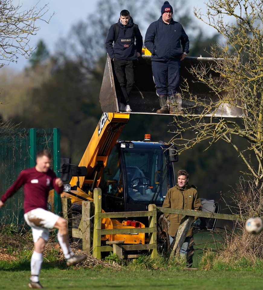 Fans watch the match from a digger bucket