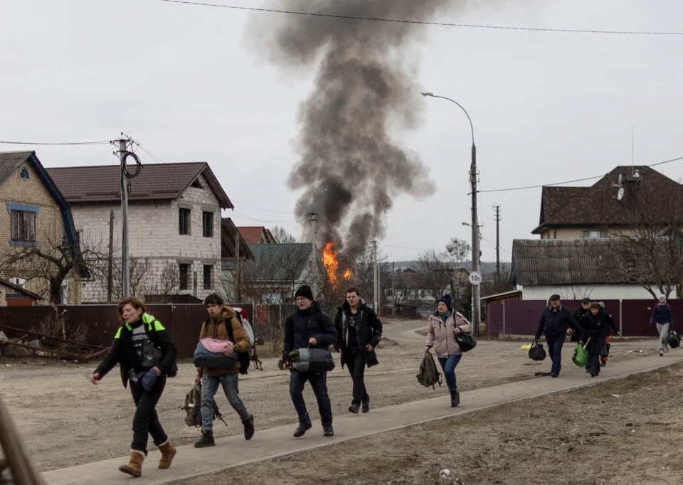 Local residents look for cover as they escape from the town of Irpin