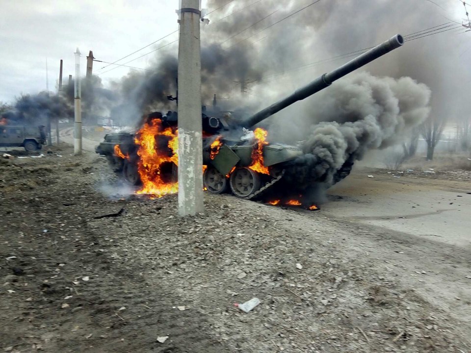 Destroyed Russian tank on fire by the side of a road in Sumy