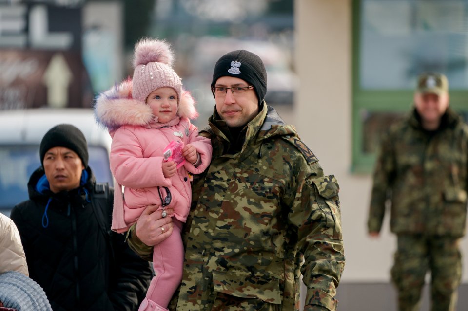 A Polish soldier helps a tot cross border from Ukraine