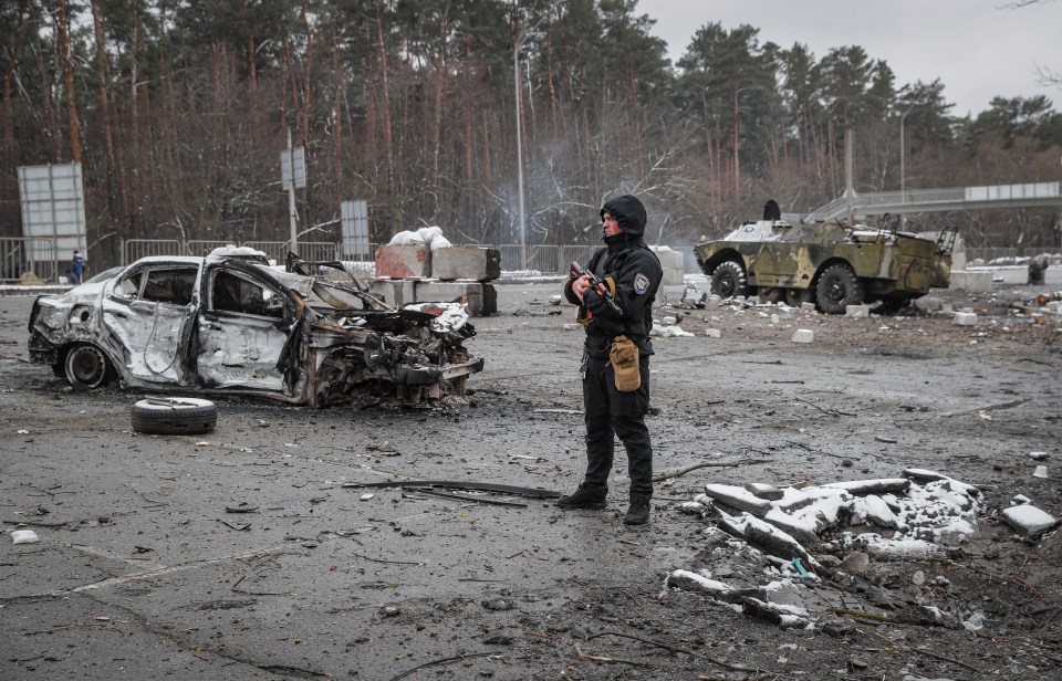 Ukrainian soldiers stand guard amid ruined cars near Kyiv