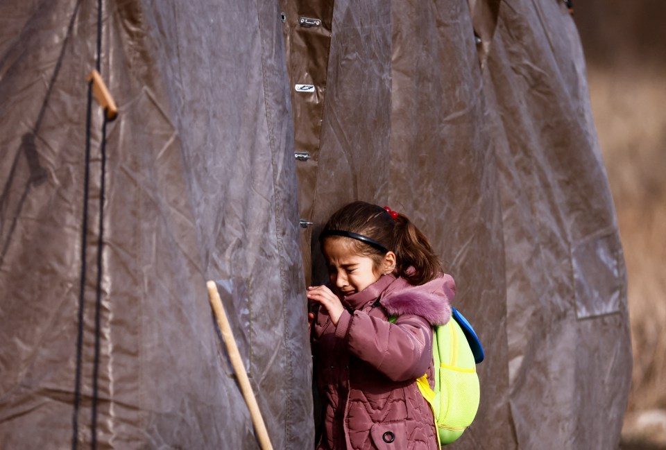 A girl weeps at entrance to a refugee camp tent in Przemysl, Poland after fleeing Ukraine