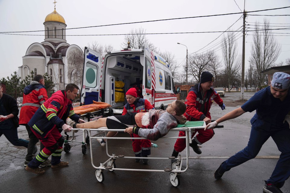 Ambulance paramedics move a stretcher with a man injured by the shelling in a residential area in Mariupol