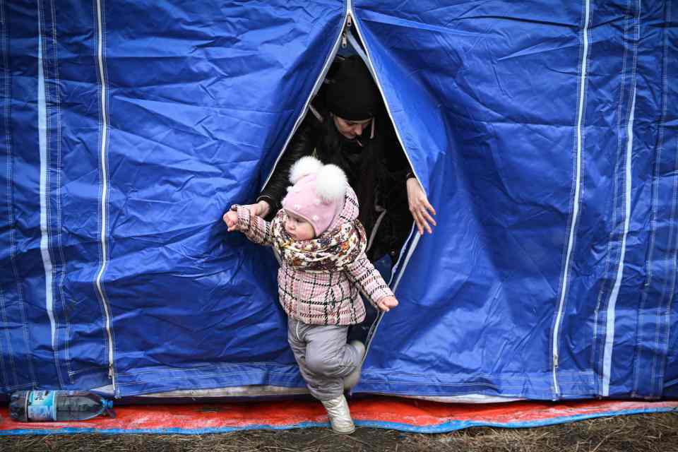 A Ukrainian mother and her child leave a tent installed by the Romanian Emergency Service at the Siret border point