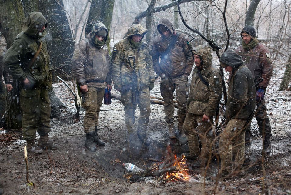 Ukrainian soldiers keep warm by a fire