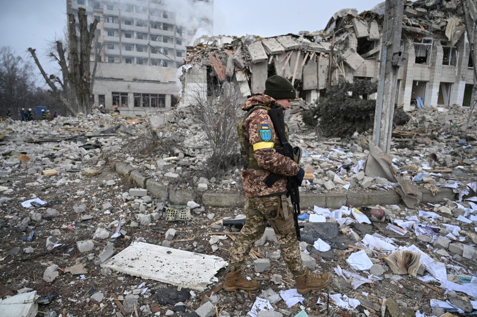 A Ukrainian service member walks near a school building destroyed by shelling in Zhytomyr