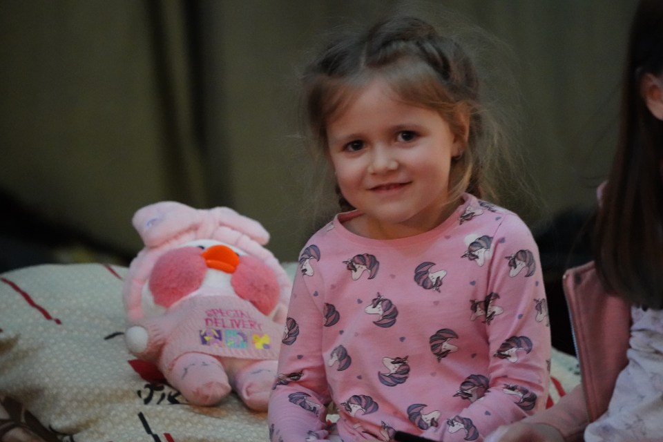 Arina's little sister Katya, 4, smiles beside her toy duck Milka after escaping the bombing in Kyiv