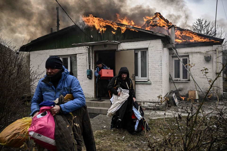 People remove their belongings from their burning house in Irpin