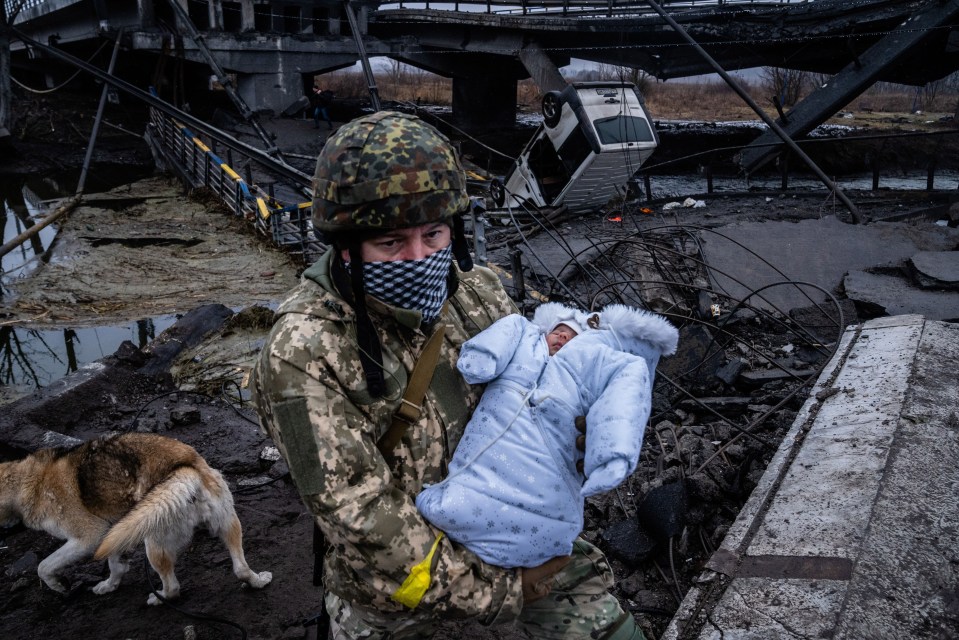 A soldier carries a baby through the rubble in Ukraine