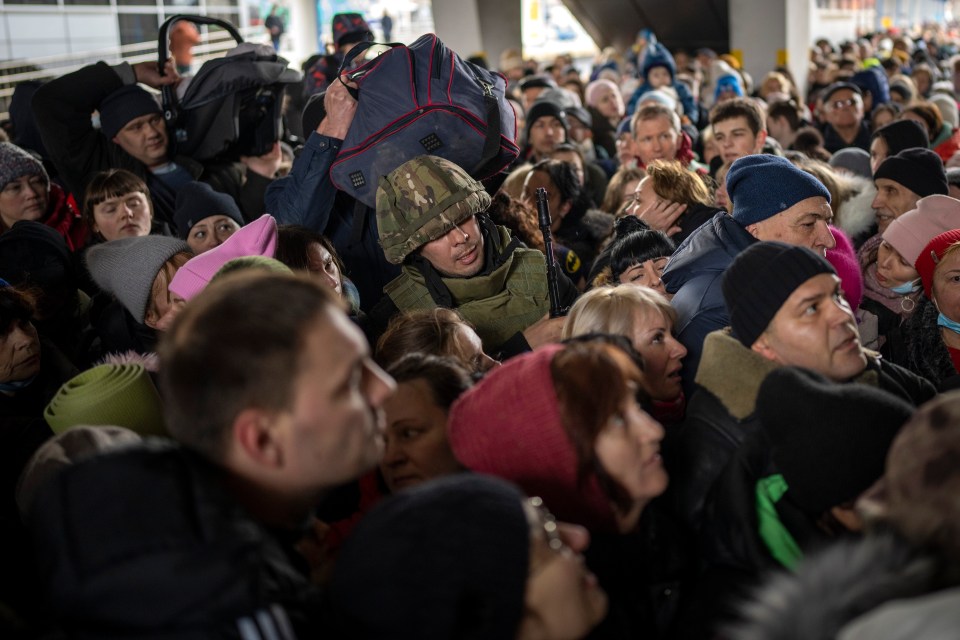 A Ukrainian soldier tries to control a crowd as civilians push to enter the train to Lviv at the Kyiv station